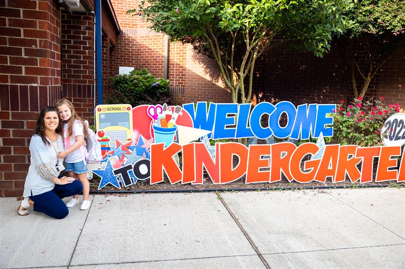 A family stands in front of a first day sign